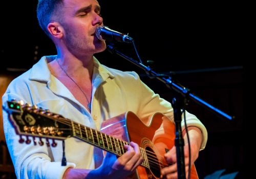 A person is playing an acoustic guitar and singing into a microphone, with 