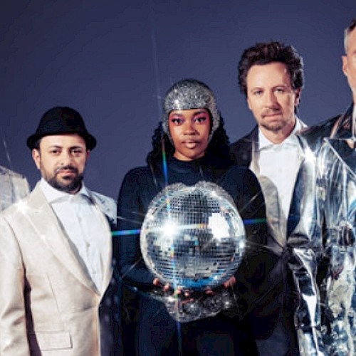 A diverse group of five people wearing stylish and shiny clothing, holding a disco ball, with a dark background and dramatic lighting.