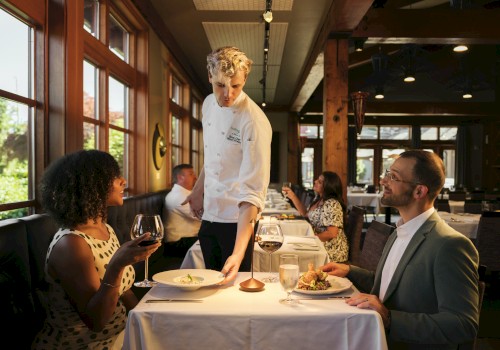 A waiter serves food to a woman and man at a restaurant table during a pleasant dining experience.