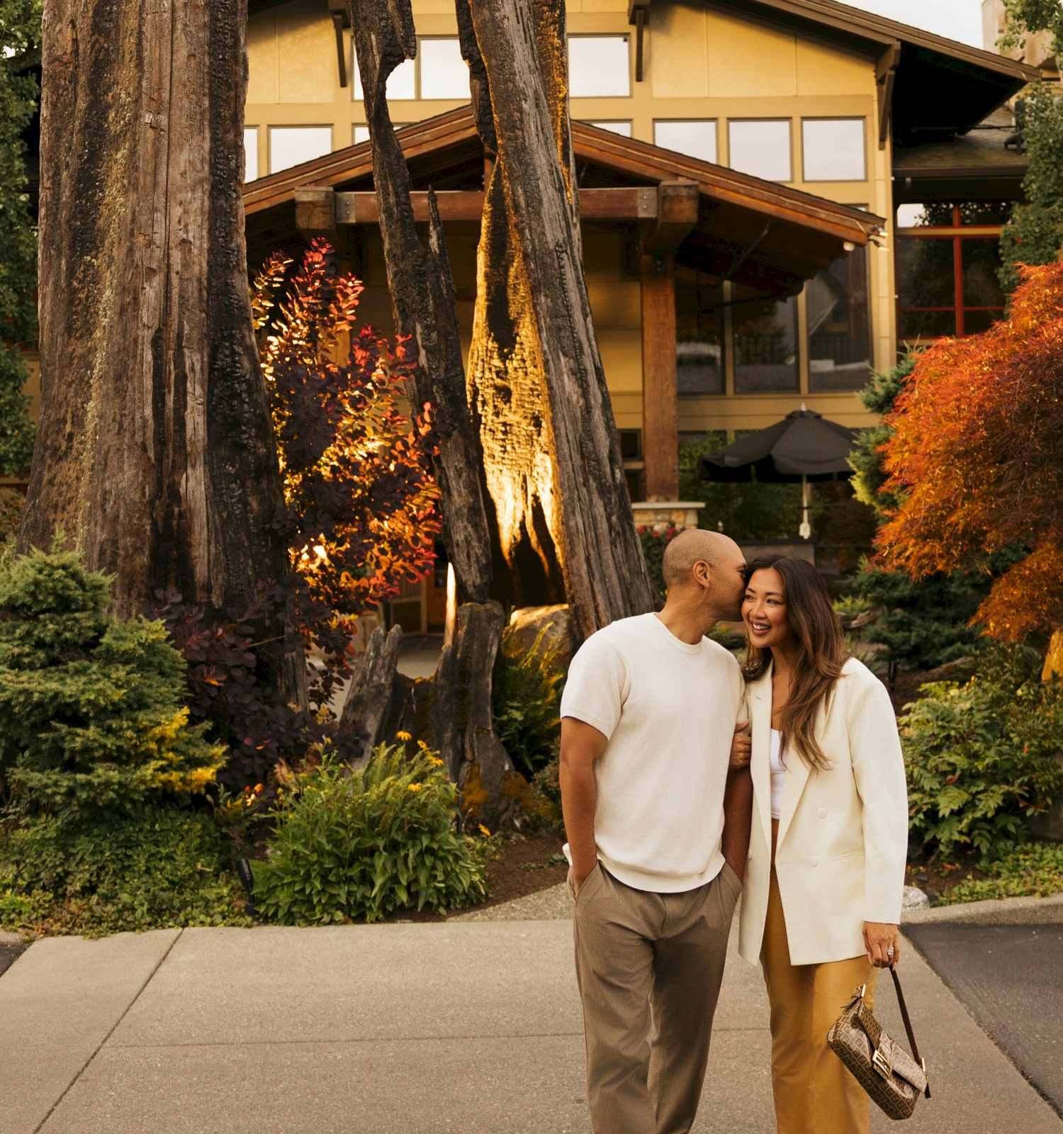 A couple sharing a romantic moment outdoors in front of a cozy house during autumn evening.