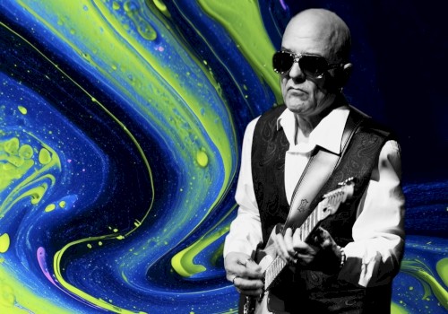 A black-and-white photo of a man playing an electric guitar against a vibrant, swirling yellow and blue abstract background.