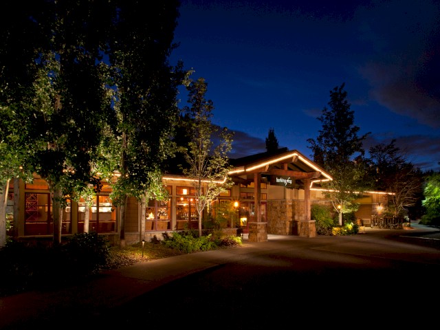 A cozy restaurant named Barking Frog with warm lights and trees outside at night.