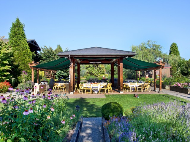 An outdoor garden with a shaded dining area and colorful flowers under a clear blue sky.