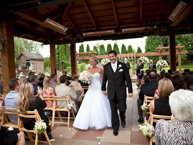 A newlywed couple walks hand-in-hand down the aisle after exchanging vows during their outdoor wedding ceremony.