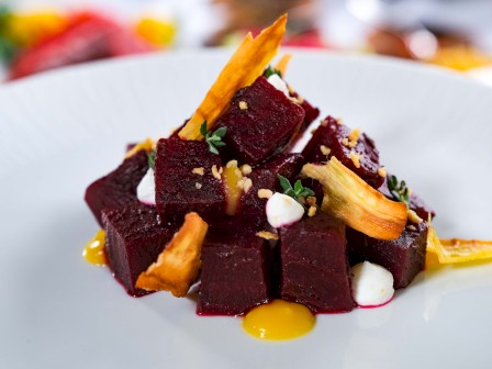 The image shows a gourmet dish with beet cubes, garnished with crispy elements and sauce on a white plate.