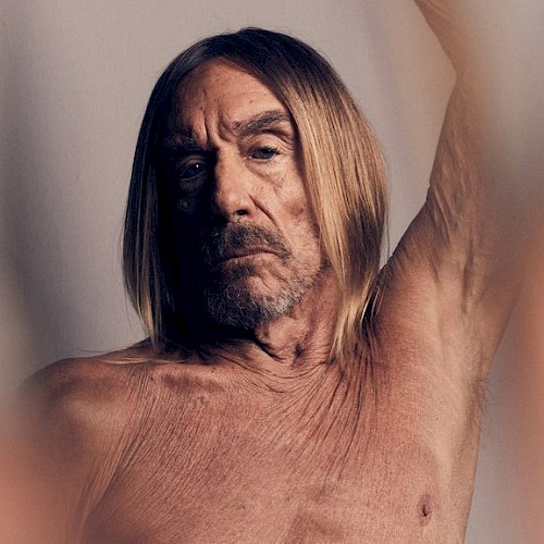 A man with long hair with one arm raised above his head