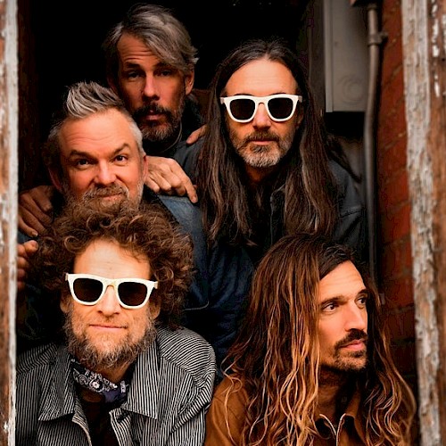 Five men in a doorway looking at the camera or to the side, some with sunglasses