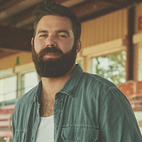A man looking at the camera with bleachers in the background