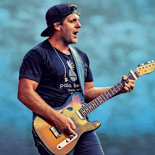 A man with a backwards hat playing a guitar and singing