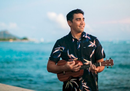 Man standing on a beach playing the ukulele