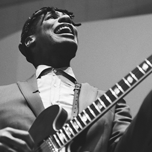 A musician passionately playing an electric guitar while singing, captured in black and white.